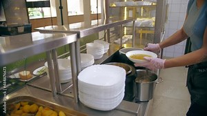 buffet restaurant. self-service cafeteria. close-up. waitress, in protective gloves, pours hot soup into a bowl for customer. cooking. health food.