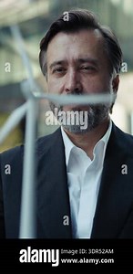 Portrait of mature entrepreneur studies miniature windmill model as stands in downtown vertical shot. Aged company manager works on sustainable technology integration for business Stock Video Footage - Alamy