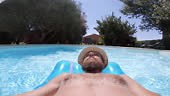 Hombre flotando en piscina con colchón de aire