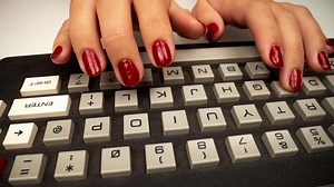 A vintage computer keyboard with the hands of a woman typing