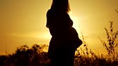 Embarazada sintiendo y tocando suavemente su barriga en siluetas.