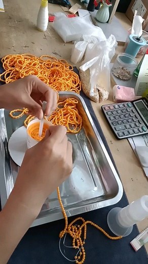 Asian Technology on Instagram: "Stringing small artificial pearls onto a thread with precision using a needle, rotating a cylinder filled with pearls to guide each one onto the needle by hand. A delicate and intricate process, each pearl aligns perfectly as the worker's steady hand threads them in place. This traditional craft blends patience and skill, creating beautiful pearl jewelry or decorations one by one. A mesmerizing and satisfying process to watch!"
