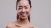 Facial cosmetics. Portrait of young asian woman applying cream smear...