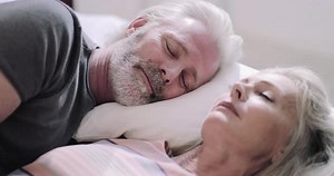 Senior Adult couple on holiday sleeping in hotel bed