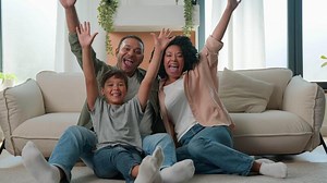 Happy multiracial family African American parents Caucasian child little boy on floor in living room own apartment mom dad kid home celebration excited father mother son raise hands together fun joy