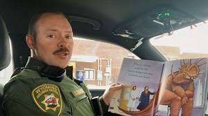 Trooper Robinson reading "How Do Dinosaurs Get well Soon" #yourWHP | Wyoming Highway Patrol