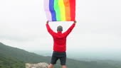 L’homme lever arc-en-ciel couleur LGBTI drapeau ondulant dans le vent...