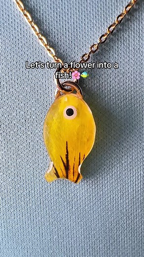 A fish charm… made out of a flower!? The stripes on this pansy made for a perfect fish-like pattern! You can purchase this fish necklace on my website (link in bio)🐠 #realflowerjewelry #fishnecklace #flowerart #crafting