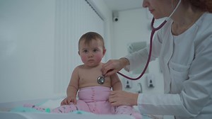 Pediatrician doctor concept. Children medical care. One year old baby girl examined by female pediatrician in clinic office. Child visiting doctor for health check-up. Doctor examine little patient.