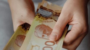 Female hands counting Canadian Dollar bills, close-up.