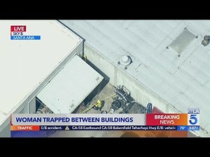 Crews work to rescue woman trapped between buildings in Santa Ana