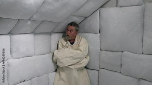 Crazy man in straight jacket in an asylum mental hospital padded cell.