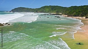 Australian coast with a long beach along the coast, view from a cliff on the seaside landscape. Strongly foamy water in windy weather.