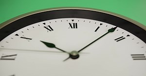 Download Close up, The white wall clock shows the passage of time. The short hand and the long hand are working to move the time. On the green background. for free