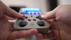 Close-up in shallow depth of field. Unrecognizable portable retro console in hands of young Caucasian woman. Girl plays retro games holding retro device for emulating old console games