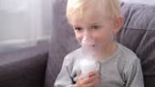 Close up portrait of cute little blond toddler boy spraying...