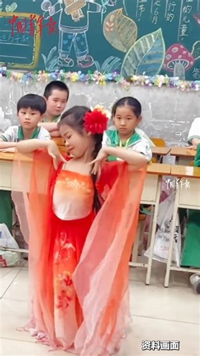 An 8-year-old girl performs a traditional fan dance under the setting sun, with graceful posture and crisp movements. #AmazingKids | China News 中国新闻网
