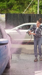 Woman washing a car at a self-service car wash | Premium Stock Video Footage