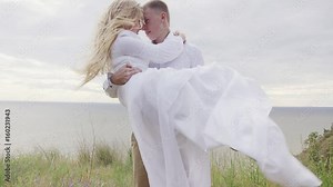 Man carrying wife in his arms on sea beach. Husband holding pregnant wife in arms on beach. Pregnant couple on sea beach. Man carrying woman in arms. Carrying woman. Man holding woman Stock Video