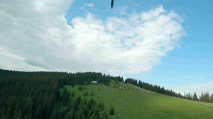 Unusual view of a woman riding a zip line among the mountains. Fast and maneuverable flight around a person