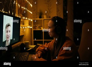 Long distance video call, man and woman using videoconference application for virtual communication, online meeting, side view. Dark, festive home atm Stock Photo - Alamy