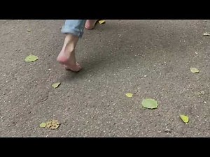 barefoot girl in jeans walking along a path in the park