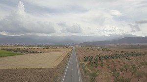 4K Aerial View Of Straight Tarred Road Through Guadix, Granada. In the background Sierra Nevada