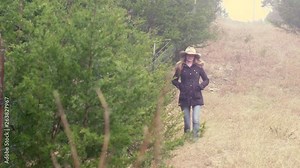 Female farmer walks along fence line in early morning