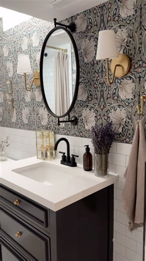 Five ways to cozy up your builder grade bathroom. One, consider putting up wallpaper in the space. It makes the most impactful change and it instantly feels more intimate. Two, pull a colour from the wallpaper and repeat it in the textiles like the shower curtain, towels and bath mat. Three, intentionally mixed metals. Here I paired brass hardware and black fixtures which creates interest to your space. Four, style with vintage finds so it feels less cookie cutter and more curated to your person