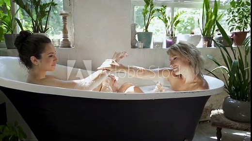 Romantic lesbian couple taking bath together and relaxing. Slowmotion.