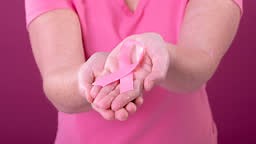 Video of midsection of caucasian woman holding pink cancer awareness...