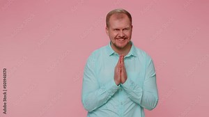 Sneaky cunning man with tricky face gesticulating and scheming evil plan, thinking over devious villain idea, cunning cheats, jokes and pranks. Young guy on pink studio wall background alone indoors