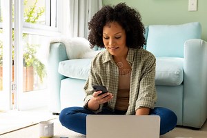 Happy Biracial Woman Using Laptop and Smartphone Sitting on Floor in Bedroom Stock Photo - Image of female, young: 283126108