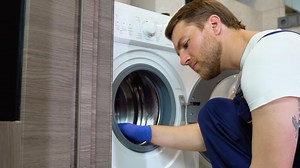 A man in blue gloves cleans a dirty, moldy rubber seal on a washing machine. Mold, dirt, limescale in the washing machine. Periodic maintenance of household appliances