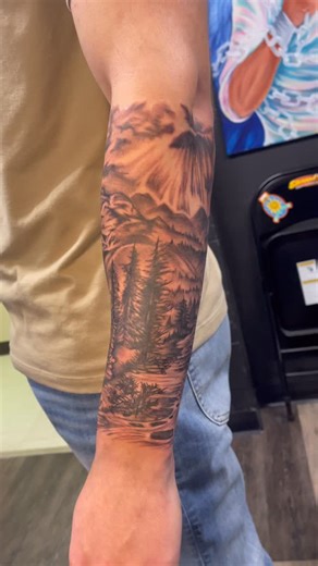 Wrapped up this black & grey landscape yesterday. A quiet mountain river winding through the trees, light breaking through the clouds above, and that soft atmospheric fade that makes the whole piece feel like it’s moving. I love tattoos that pull you into a scene.. where the shading, depth, and texture create a world on the skin. Grateful for clients who trust me to build something timeless and custom to their arm. If you’ve been thinking about a landscape tattoo or a piece that tells a story, m