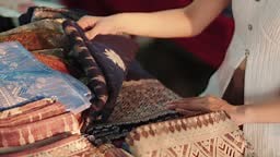 Female tourist choosing delicate sarongs at the local clothing store.