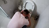 Young man vomits in toilet food poisoning. Vomiting causes diagnosis...