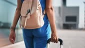 Closeup active female tourist carrying suitcase and backpack going to...