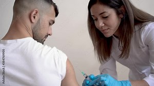 COVID‑19 vaccine. Female nurse giving injection to a male patient.