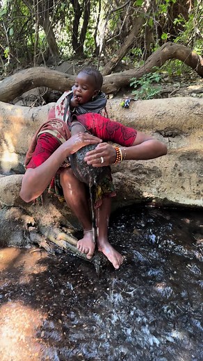 Hadza Woman Showering in Natural River Water