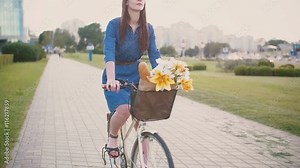 Happy girl in a dress cycling and exploring the city, slow mo, steadicam shot