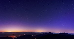 The stars revolve in the starry night sky over the mountains. 4K