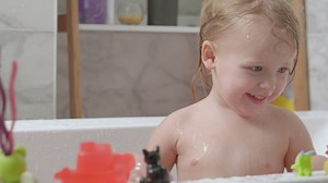Little girl playing in the bath and splashing water