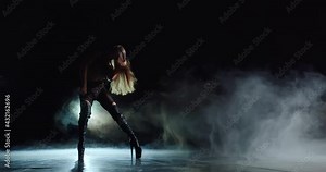 A sweet and attractive woman demonstrates a strip dance on stage. She is erotic, smoothly and clearly moves her body. She runs her hands over her legs, through her hair, bends in the lower back
