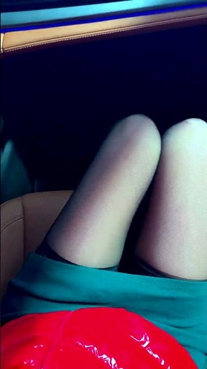 The girl lifts her skirt in the car and shows her black stockings