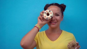 Woman eating donuts at a blue wall background
