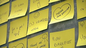 Pink and yellow adhesive post-it notes on the wall forming a 'to do' words.