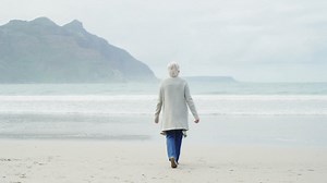 Rear view of senior woman walking on beach | Premium Stock Video Footage