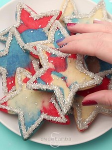 Celebrate the 4th of July with these fun, easy, and delicious cookies. This is a great project for all ages! Get the supplies to make these cookies yourself: https://globalbelly.com/collections/sweetambs/products/sweetambs-4th-of-july-star-cookies-supplies #cookiedecorating #sweetambscookies #cookies #summercookies #royalicing #decoratedcookies #celebratewithcookies #4thofjulycookies #independencedaycookies #sweetambs #kidsinthekitchen | SweetAmbs