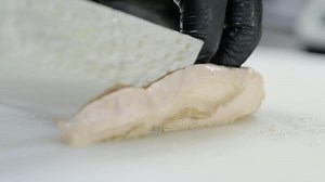 cook cuts chicken meat with a beautiful knife